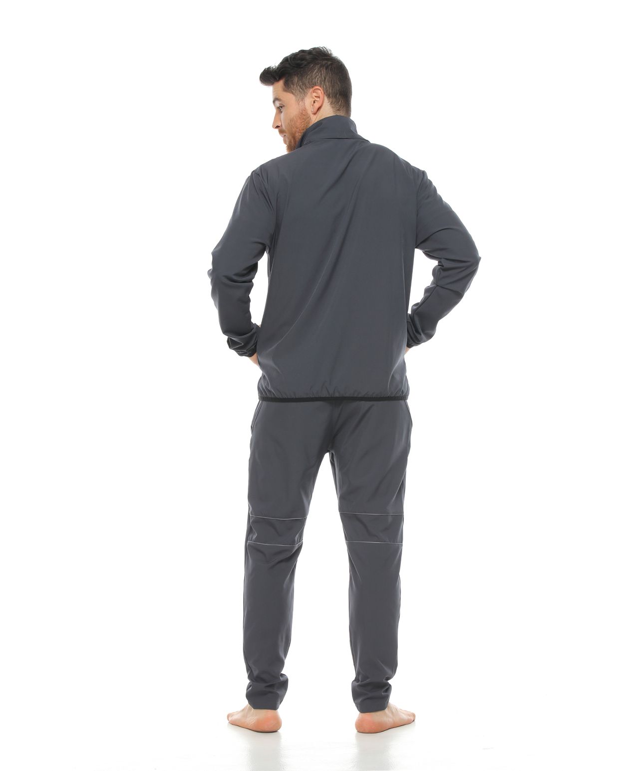 Modelo con pantalon deportivo color gris oscuro para hombre y chaqueta color gris oscuro parte trasera