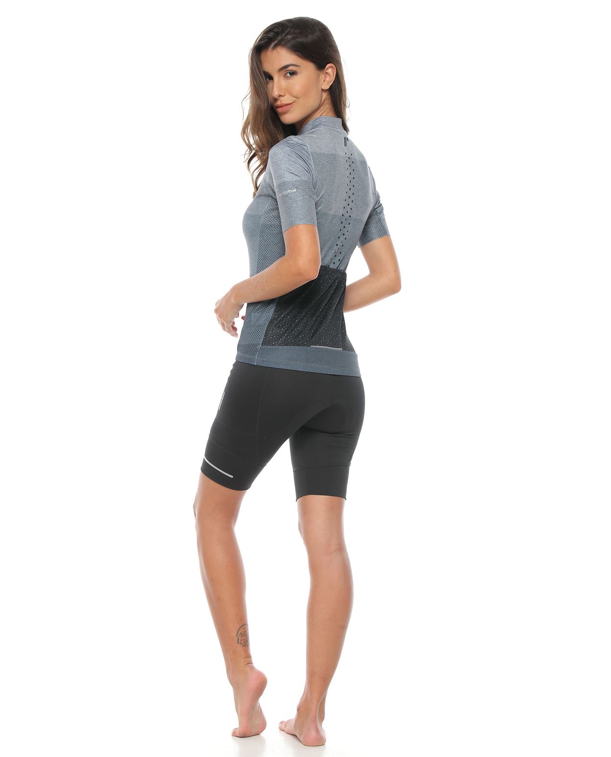modelo con licra corta con badana color negro para mujer y camiseta de ciclismo unisex color gris cuerpo completo parte trasera