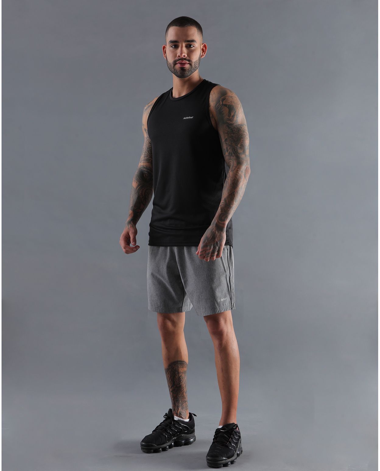 modelo con camiseta basica color negra y pantaloneta deportiva color gris para hombre cuerpo completo