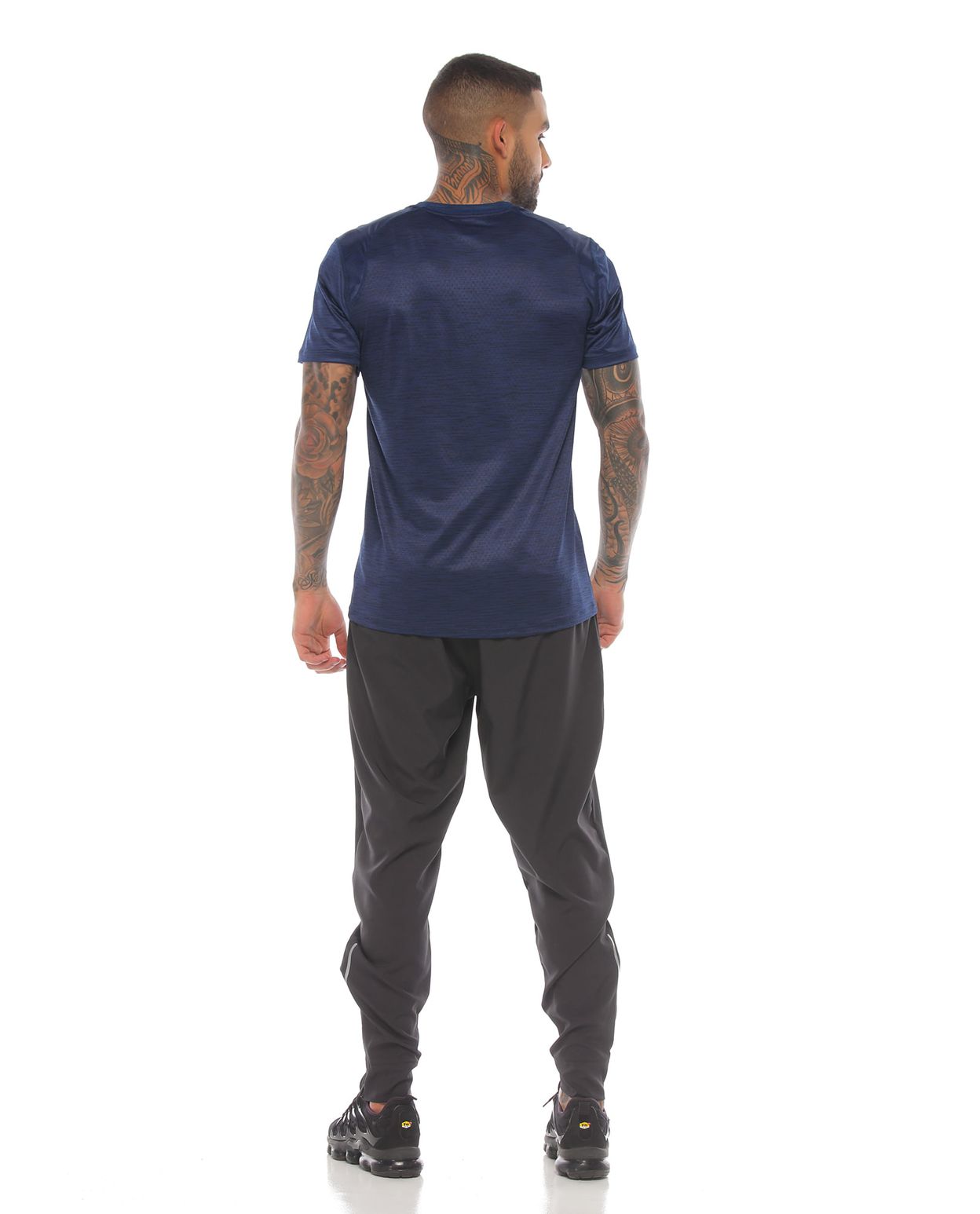 modelo con camiseta azul oscuro manga corta y pantalon deportivo gris para hombre cuerpo completo parte trasera