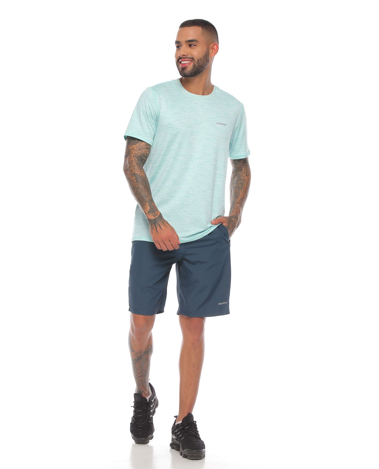 modelo con pantaloneta deportiva color petroleo y camiseta deportiva color verde para hombre cuerpo completo parte frontal