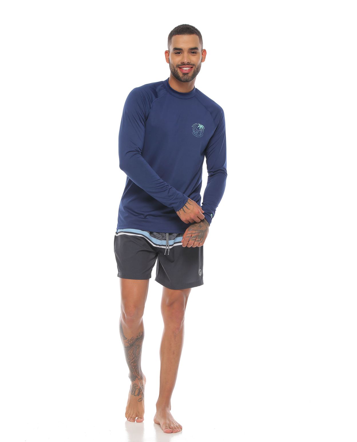 modelo con camibuso proteccion uv color azul oscuro y pantaloneta de playa color gris para hombre cuerpo completo
