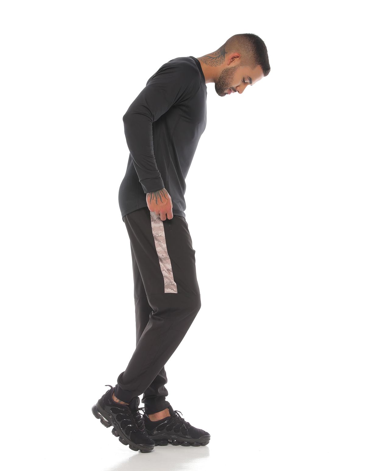 modelo con pantalon y camibuso deportivo color negro arena para hombre cuerpo completo parte lateral derecha