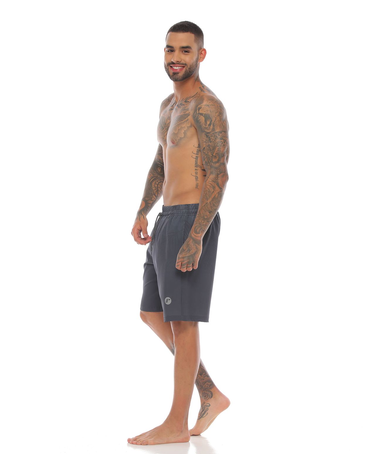 modelo con pantaloneta de playa larga color gris oscuro para hombre cuerpo completo parte lateral izquierda
