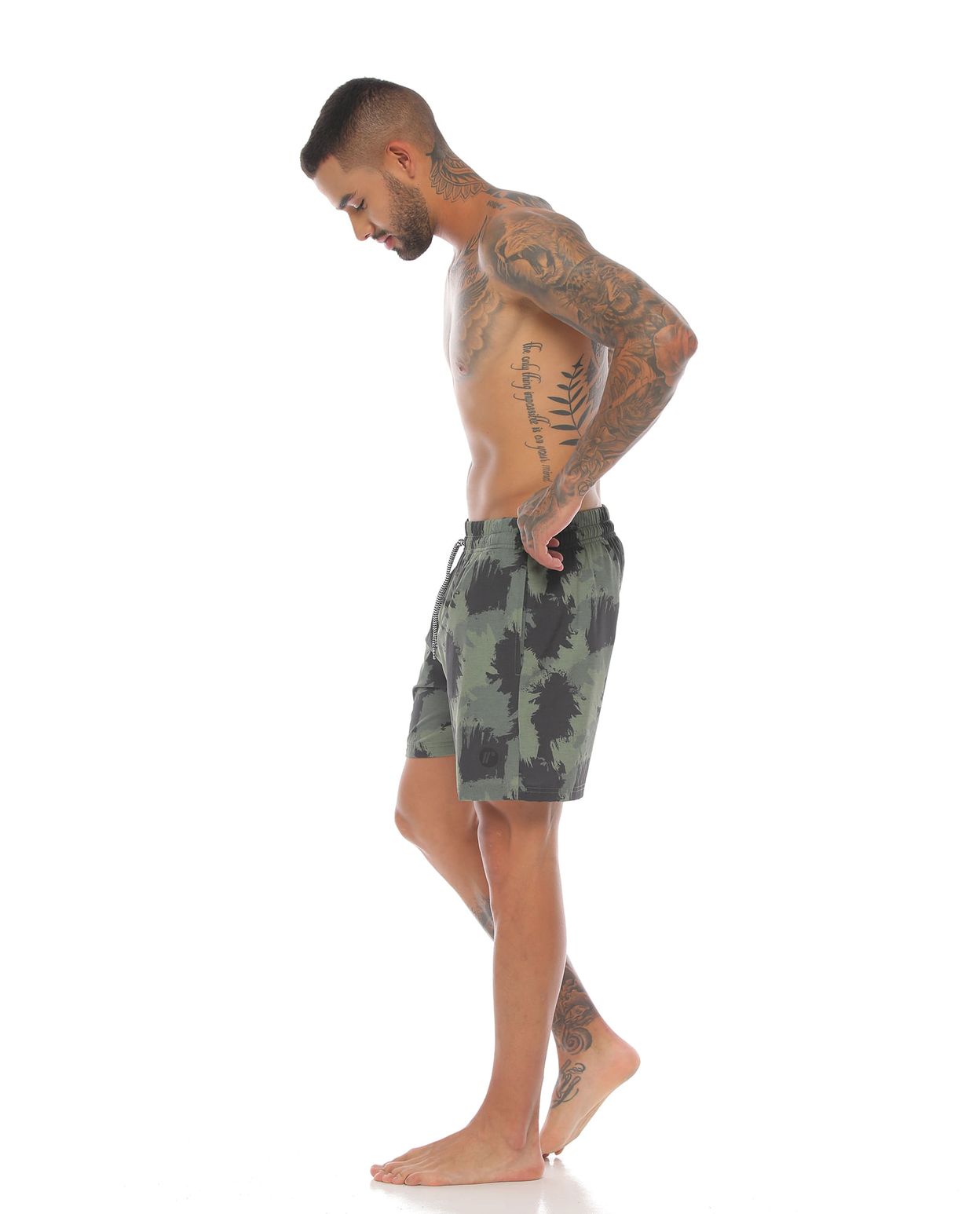 modelo con pantaloneta corta de playa color verde militar para hombre cuerpo completo parte lateral izquierda