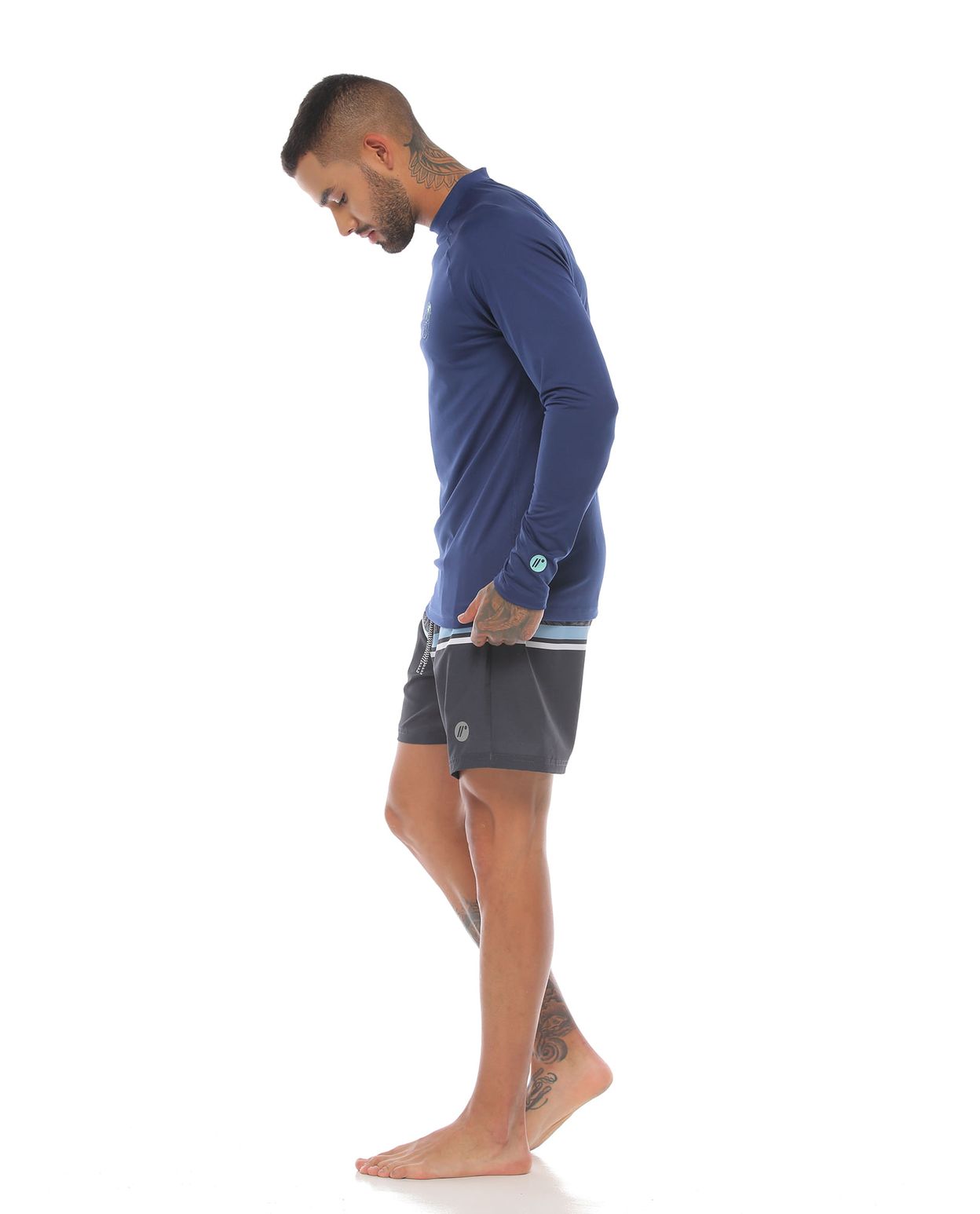 modelo con pantaloneta corta de playa color negro y camibuso color azul para hombre cuerpo completo parte lateral izquierda