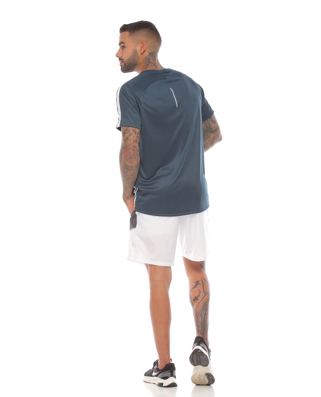 modelo con camiseta deportiva color petroleo y pantaloneta deportiva blanca para hombre cuerpo completo parte trasera