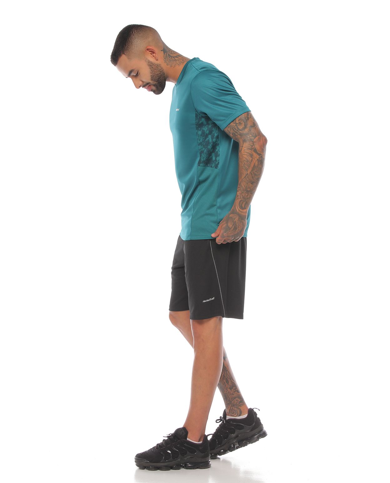 modelo con camiseta deportiva manga corta color verde y pantaloneta deportiva negra para hombre parte lateral izquierda